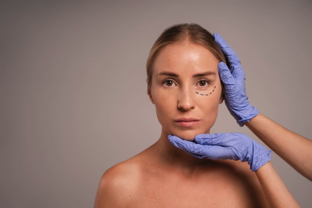 esteticista con guantes azules valorando cara de paciente para tratamiento estetico